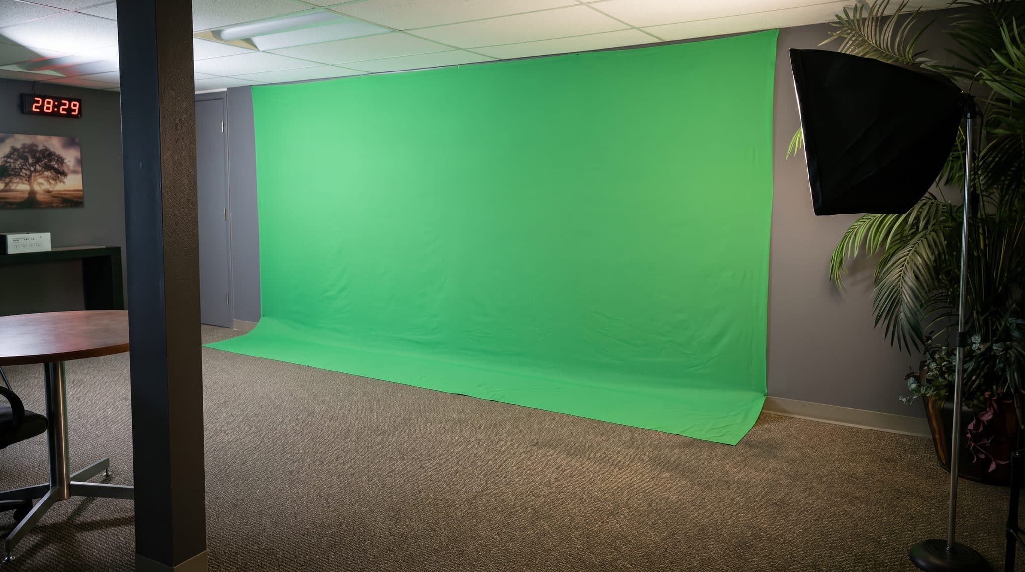 The green screen studio, a wide green backdrop sweeping from the wall down to the floor with a softbox light on a stand beside it